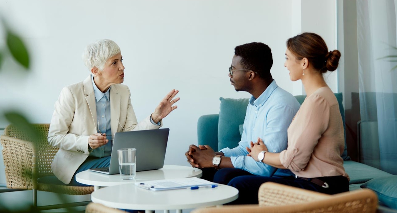 young couple in an office talking to woman ta laptop