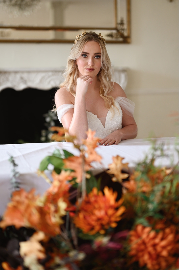 bride sat at table in front of burnt orange flowers