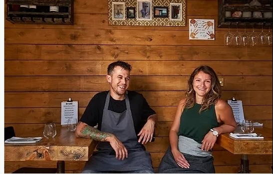 man and lady wearing aprons sitting in restaurant