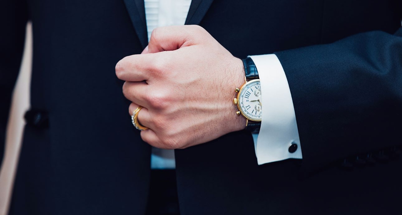 groom in suit adjusting button with watch on