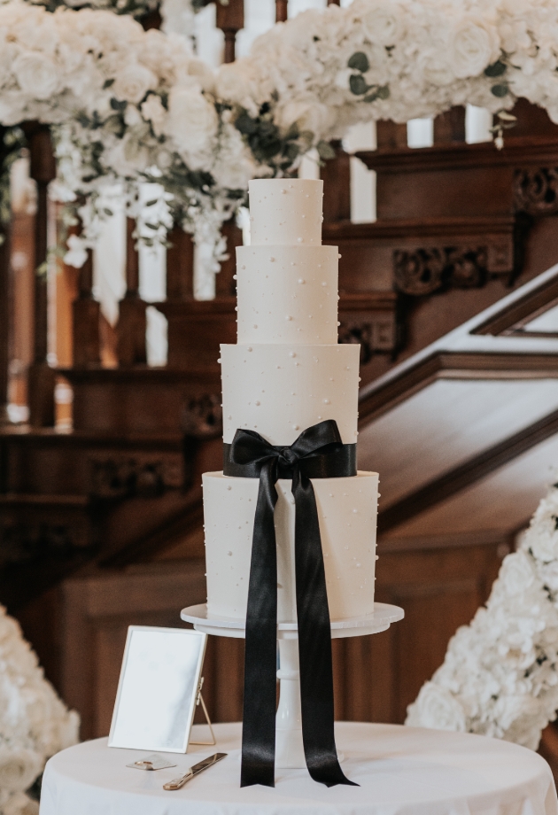 white wedding cake with black ribbon